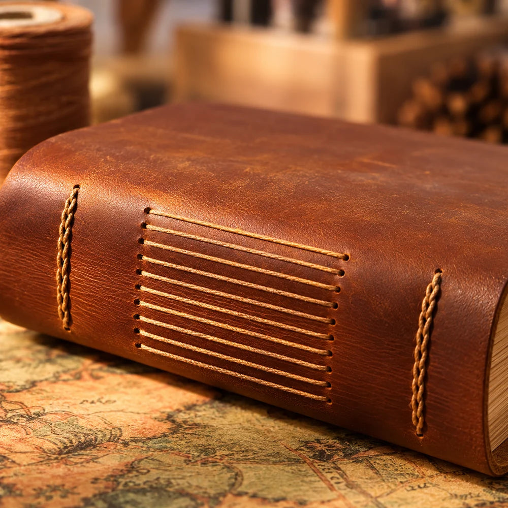 Close-up of tan cord stitching and natural grain along the chestnut brown cowhide journal spine.