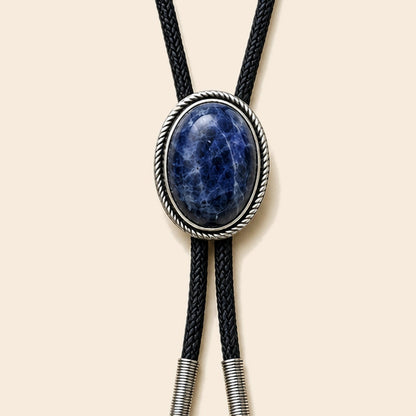 Blue Ridge blue stone bolo tie with antique silver-tone frame and black cord on a warm ivory background