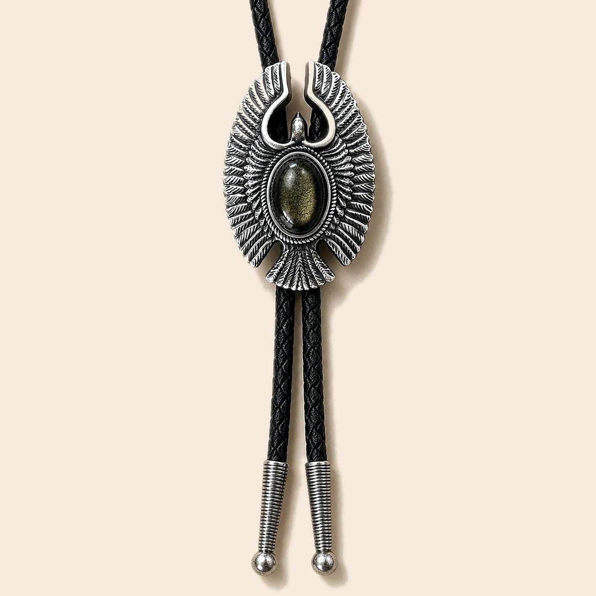 Eagle Wing golden obsidian bolo tie with antique silver-tone eagle frame and black braided cord on a warm ivory background