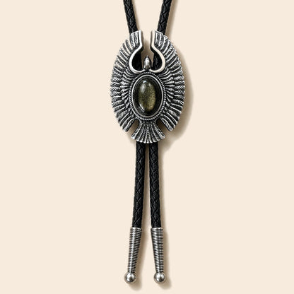 Eagle Wing golden obsidian bolo tie with antique silver-tone eagle frame and black braided cord on a warm ivory background