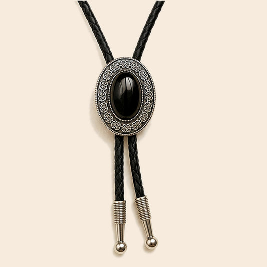 Midnight Mesa black obsidian bolo tie with antique silver-tone frame and leather cord on a warm ivory background