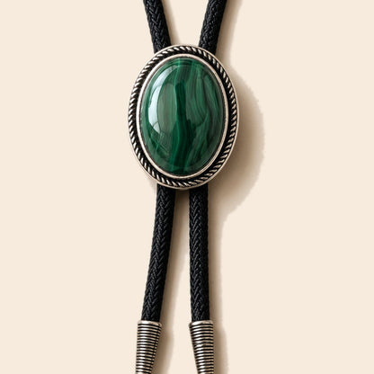 Sage Valley malachite bolo tie with green malachite stone and black cord on a warm ivory background