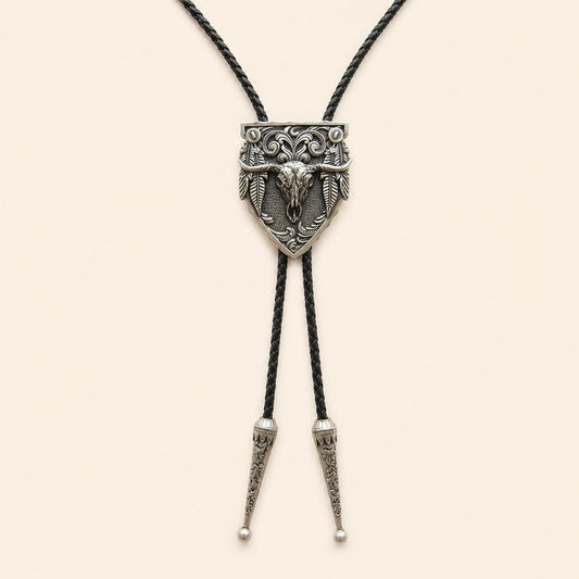 Silver longhorn arrowhead bolo tie with feather details and braided leather cord on warm ivory background