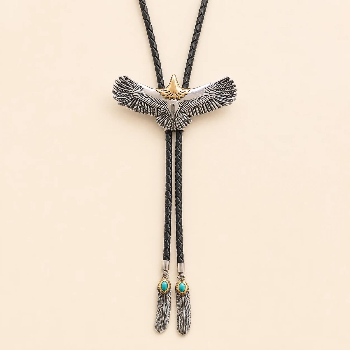 Stainless steel soaring eagle bolo tie with a titanium-gold-tone eagle head and feather tail tips on a warm ivory background