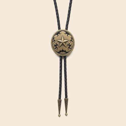 Antique brass Western star bolo tie with black braided leather cords on a warm ivory background