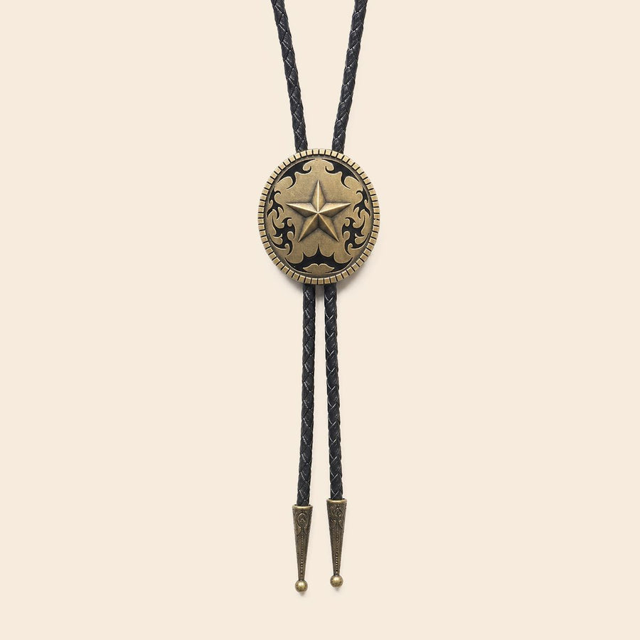 Antique brass Western star bolo tie with black braided leather cords on a warm ivory background