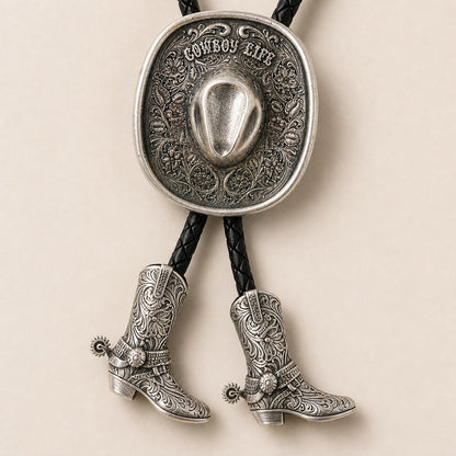 Close-up detail of silver Cowboy Life hat bolo tie with floral tooling and cowboy boot pendants