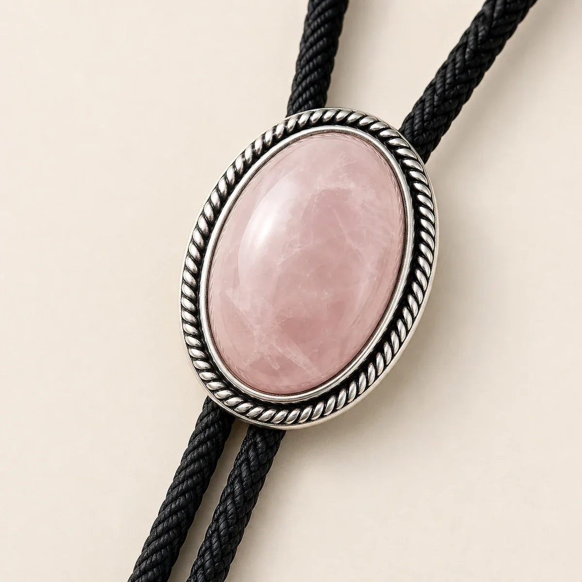 Close-up of rose quartz bolo tie with silver-plated rope border frame