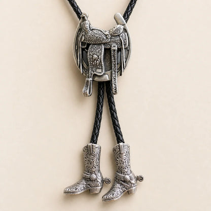 Close-up of silver saddle bolo tie with engraved tooling and separate cowboy boot pendants