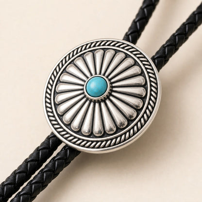 Close-up detail of a turquoise-tone concho bolo tie with antique silver-plated frame
