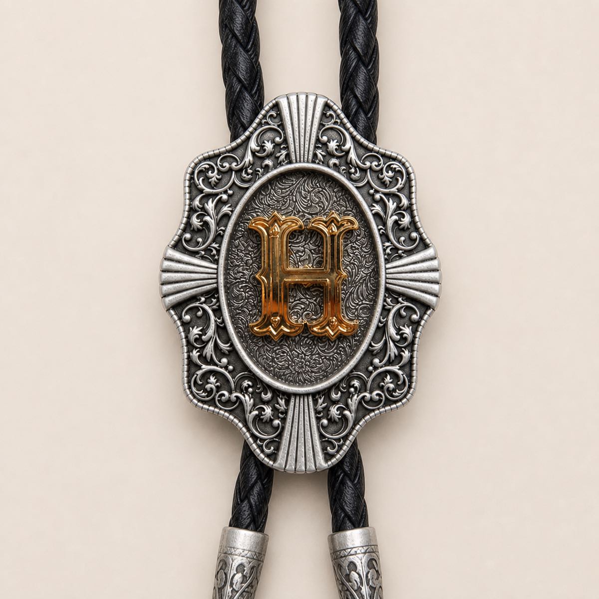 Detailed view of ornate gold letter H bolo tie slide