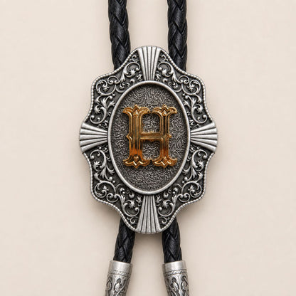 Detailed view of ornate gold letter H bolo tie slide