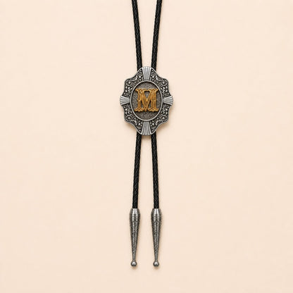 Gold letter M western bolo tie on pale warm ivory background