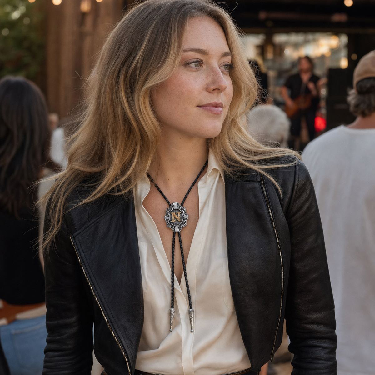 Young woman wearing gold letter N bolo tie at an outdoor music event