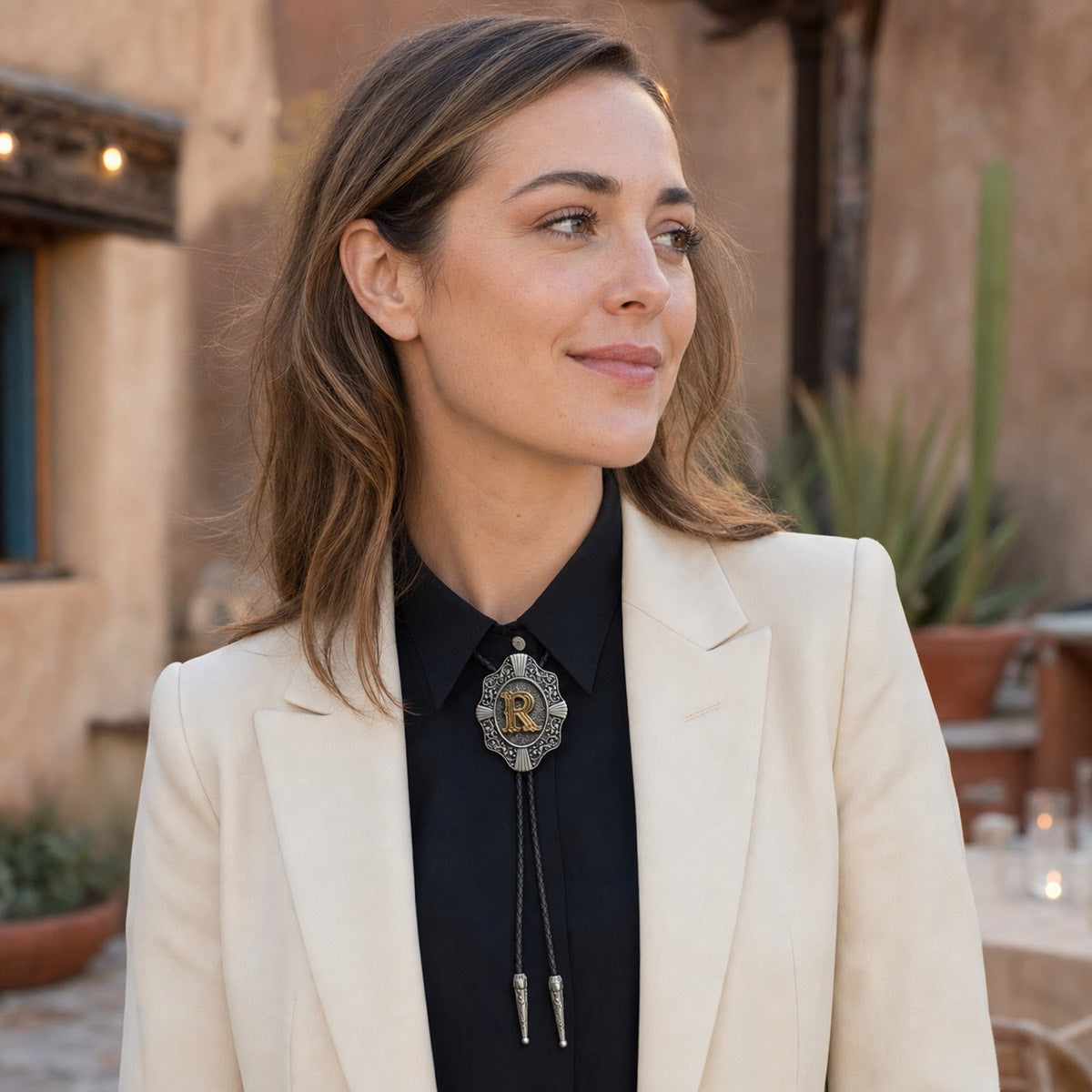 Young woman wearing gold letter R bolo tie at a Southwestern wedding reception