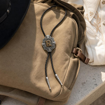 Gold letter R bolo tie in a music festival travel flat lay