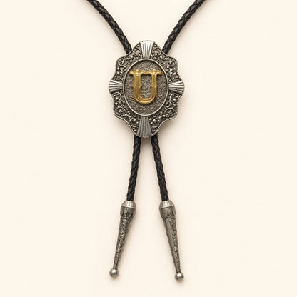 Gold letter U western bolo tie on pale warm ivory background