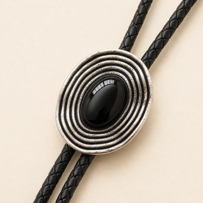Close-up detail of natural black obsidian stone and antique silver-tone irregular orbit bolo tie frame