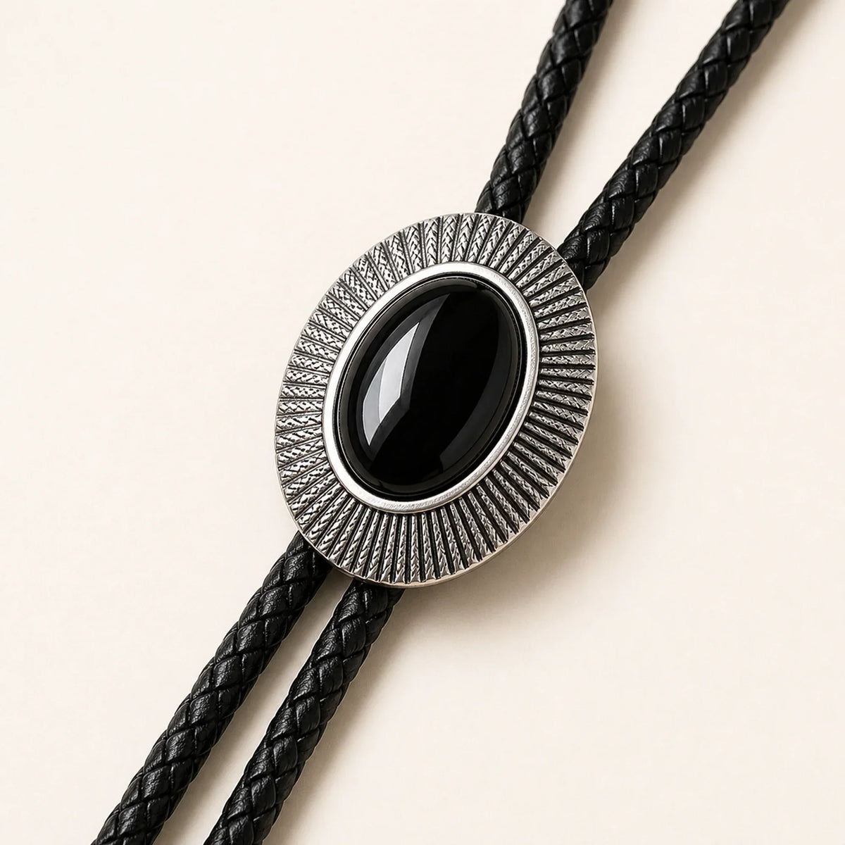 Close-up detail of natural black obsidian stone and antique silver-tone sunburst frame on bolo tie